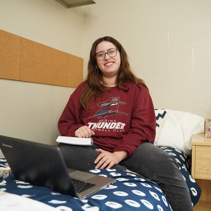 Image of Raiha Shareef outside with her diploma and medal of distinction